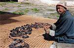 Ein älterer Mann, der Trocknung von Fleisch auf einer Matte in Bhutan