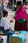 Ecuador, Two women negotiate the price of beads at Otavalo Indian Market.