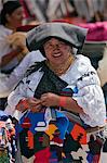 Ecuador, An indigenous Ecuadorian woman puts the final touches on her small woollen wall hangings at Otavalo market.