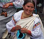 Ecuador, An indigenous Ecuadorian woman busy making a woollen hat at Otavalo market.