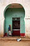 Ethiopia, Harar. A woman walks past a butcher in the Harar Muslim meat market.