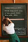 Lyon, France. A waitress in a french cafe writes the days specials on the chalkboard