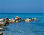 Fille au soleil sur les rochers sur la plage de Boussolos