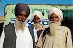 Inde, Rajasthan, Pushkar. Un groupe de pèlerins à chameau de plus grand du monde équitable, regarder sévèrement la caméra comme ils marchent à travers les marchés alimentaires.