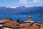 View of Lake Maggiore showing typical red roofs and snow capped mountains.