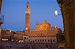 Italien, Toskana, Siena. Touristen besuchen die Piazza del Campo, Sienas mittelalterlichen Hauptplatz deren Mittelpunkt der Palazzo Publico (Rathaus) mit dem 102 m hohen Glockenturm, der Torre del Mangia steht.