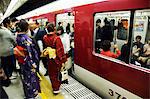 Japan,Honshu Island,Kyoto Prefecture,Kyoto City,Kyoto Station. Young women wearing Kimonos,waiting to get on a train.