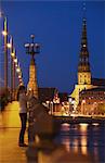 Woman taking photograph on Akmens Bridge with St Peter's in background