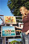 Lithuania, Vilnius, Woman Looking At Paintings At Craft Market On Pilies Gatv.