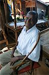 Malawi, Zomba. In the covered market area of Zomba, a stall holder relaxes and smiles up at the photographer.