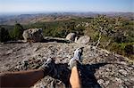 Malawi, Lilongwe, Ntchisi Forest Reserve. A trekker rests and enjoys the stunning scenery of the forest reserves viewpoint.