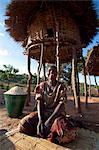 Malawi, Lilongwe, Ntchisi Forest Reserve. Dans l'ombre une jeune femme prépare la farine de mil pour sa famille.