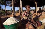 Malawi, Lilongwe, Ntchisi Forest Reserve. In the shade a young woman prepares millet flour for her family.