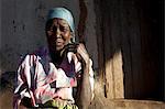 Malawi, Lilongwe, Ntchisi Forest Reserve. An old woman sits by the entrance to her hut in a mountain village.