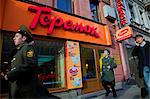 Russia, St.Petersburg; Policeman running in front of an outlet selling 'blini', traditional pancakes