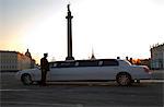 Russia, St.Petersburg; A chaffeur with a limousine in Palace Square with Alexander Column in the middle.