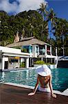 Woman sitting by pool in Bhu Nga Thani Resort and Spa, Railay, Krabi Province, Thailan.