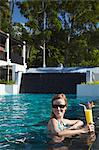 Woman relaxing in pool with drink in Bhu Nga Thani Resort and Spa, Railay, Krabi Province, Thailan.