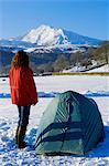 Wales, Gwynedd, Snowdonia. A camper by her tent looking towards Moel Siabod.