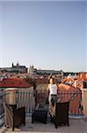 Woman leaning on roof terrace looking over Prague cityscape