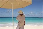 Femme sur une plage tropicale sous un parapluie