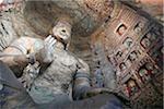 Statue and carvings in ancient Buddhist temple grotto.