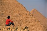 Woman on rocky outcrop looking over Pyramids