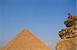 Woman on rocky outcrop looking over Pyramids