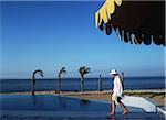 Woman in sun hat and kaftan waking along beach at Oberoi Sahl Hasheesh resort