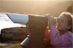 England, Cornwall, Lizard. A young girl looks through at a telescope at Lizard Point, mainland England's most southerly point.