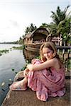 India, Kerala. Young girl on a family holiday in the Kerala Backwaters, a houseboat in the background.