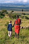 Kenya, Laikipia, Lewa Downs. A Wilderness Trails' Laikipiak Maasai guides leads children on a bush walk.