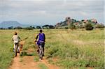 Kenya, Chyulu Hills, Ol Donyo Wuas.  A Maasai guide takes a child on a mountain biking safari.