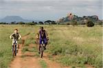 Kenya, Chyulu Hills, Ol Donyo Wuas.  A Maasai guide takes a child on a mountain biking safari..