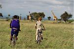 Kenya, Chyulu Hills, Ol Donyo Wuas. A Maasai guide and boy on a mountain biking safari towards Maasai giraffe.