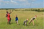 Kenya, Masai Mara.  Safari guide, Salaash Ole Morompi, shows young boys on safari how to throw a spear.