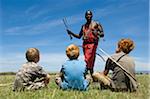 Kenya, Masai Mara. Safari guide, Salaash Ole Morompi, shows different tips on his Maasai arrows to boys on safari.