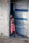 Mozambique, Ihla de Moçambique, Stone Town. A young girl in a worn, old doorway of her house in Stone Town.