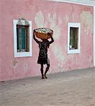 Mozambique, Ihla de Moçambique, Stone Town. A man walks with his catch through the brightly-painted buildings