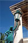 Mozambique, Ihla de Moçambique, Stone Town. A bronze Egyptian-inspired statue holds up a lantern outside a once-grand building.