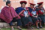 Peru, teilt ein Mann einen Witz mit einer Gruppe von einheimischen indischen Frauen in Tracht. Ihre tellerförmige Hüte, wunderschön verzierten roten Jacken, schwarze Röcke und handgewebte Wolldecken Runde ihre Schultern sind typisch für die Region.