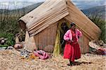 Au Pérou, une fille de Uros en dehors de sa maison sur l'un de l'uniques des îles flottantes du lac Titicaca reed.