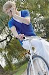 Blond man with bicycle using cell phone