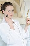 Woman in bathrobe applying make up