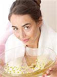 Woman holding bowl with camomile petals