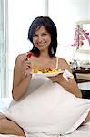 Woman in bed with plate of fruit