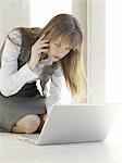 Businesswoman using laptop and cell phone on the floor