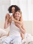 Happy couple in bed drinking coffee