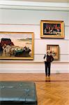 Australia, New South Wales, Sydney.  A woman looks at paintings in the Art Gallery of New South Wales.