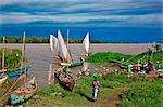 Kenya, Nyanza District. Fishermen return in their boats from fishing in Lake Victoria while women prepare to sell the catch